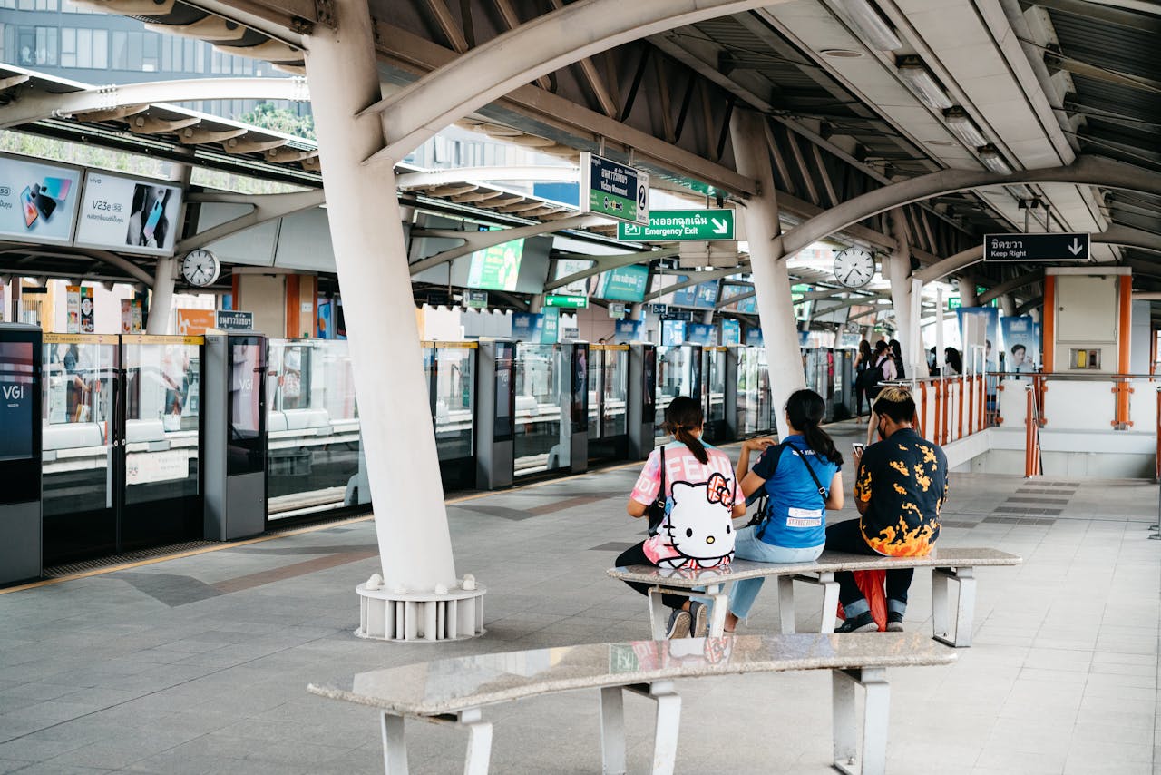 People sitting on a railway station platform, waiting for the train in an urban setting.
