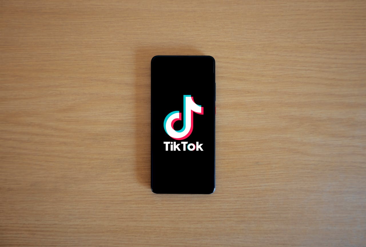 Smartphone with TikTok app displayed on black screen against a wooden background.