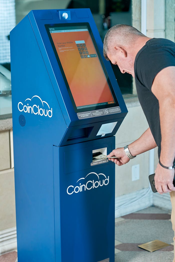 Adult male interacting with a Coin Cloud crypto ATM indoors, highlighting modern digital finance technology.